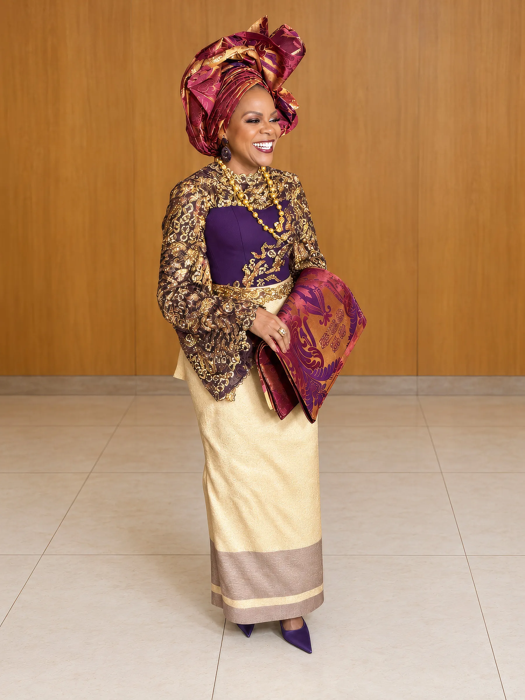 Dupe laughing, full length against wood panelling, a purple and gold hand fan under her arm. Flared lace sleeves, the strapless corset and the fitted gold skirt draw the hourglass silhouette.