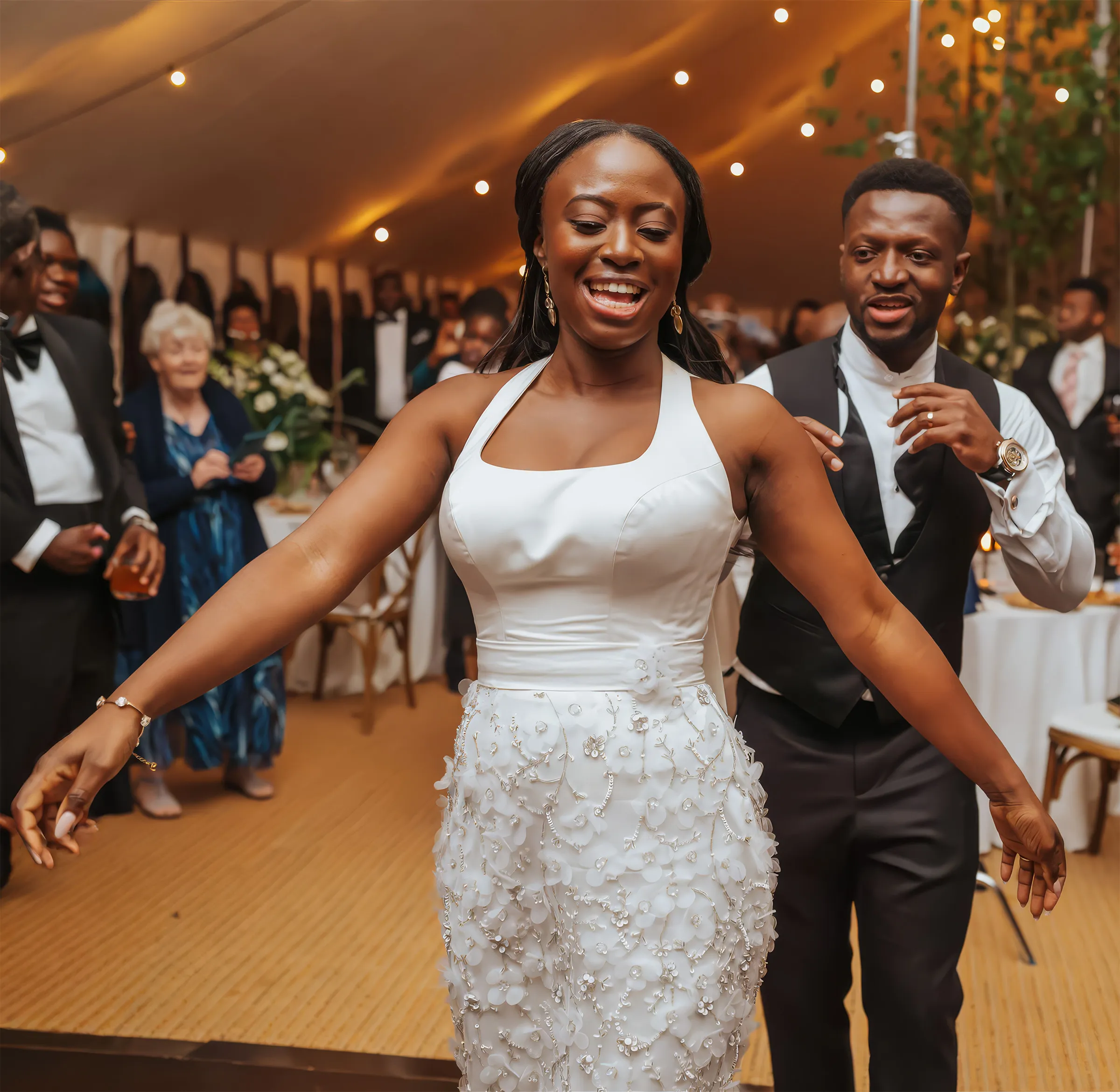 Ife dances at her evening reception at Barnston Lodge, Essex, in the embellished halter-neck column gown revealed when the overskirt came off, its skirt covered in three-dimensional floral appliqués and beadwork.