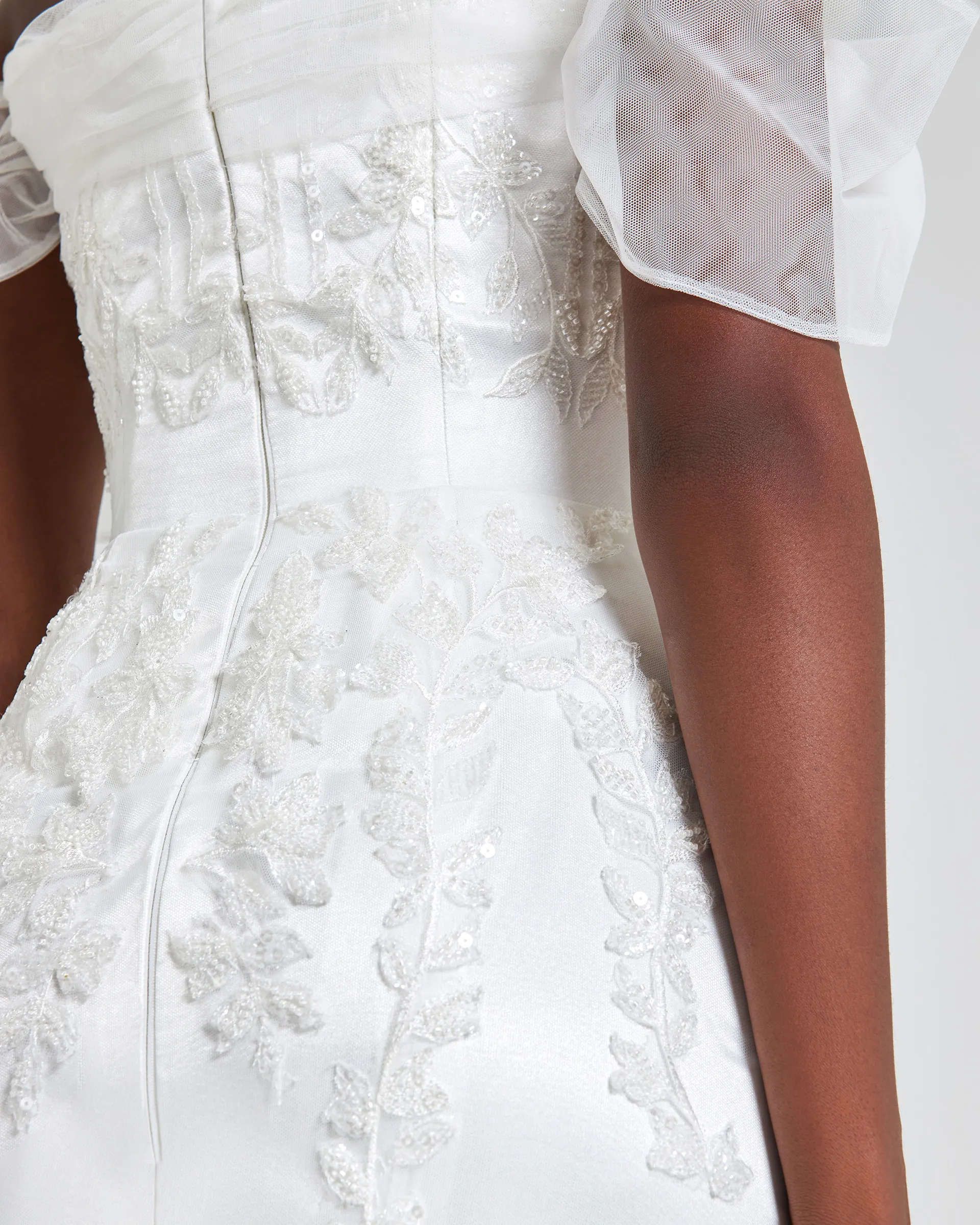 Ajoke, back detail: beaded and sequinned lace appliqués climb the fitted bodice beside a centre-back zip, below a gathered tulle sleeve.