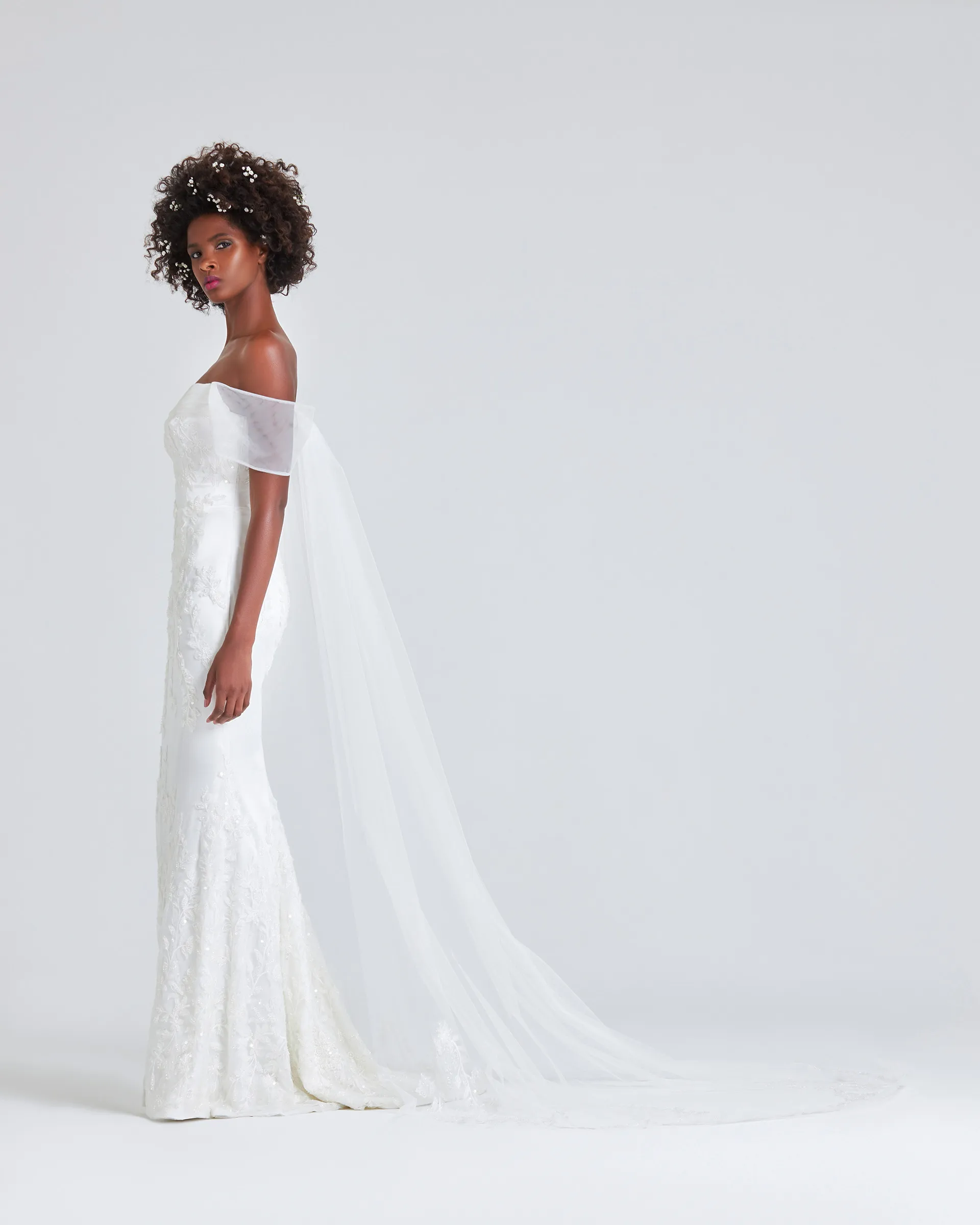 Ajoke, side: the detachable tulle Watteau train falls from the shoulders and sweeps far behind the slim trumpet skirt.