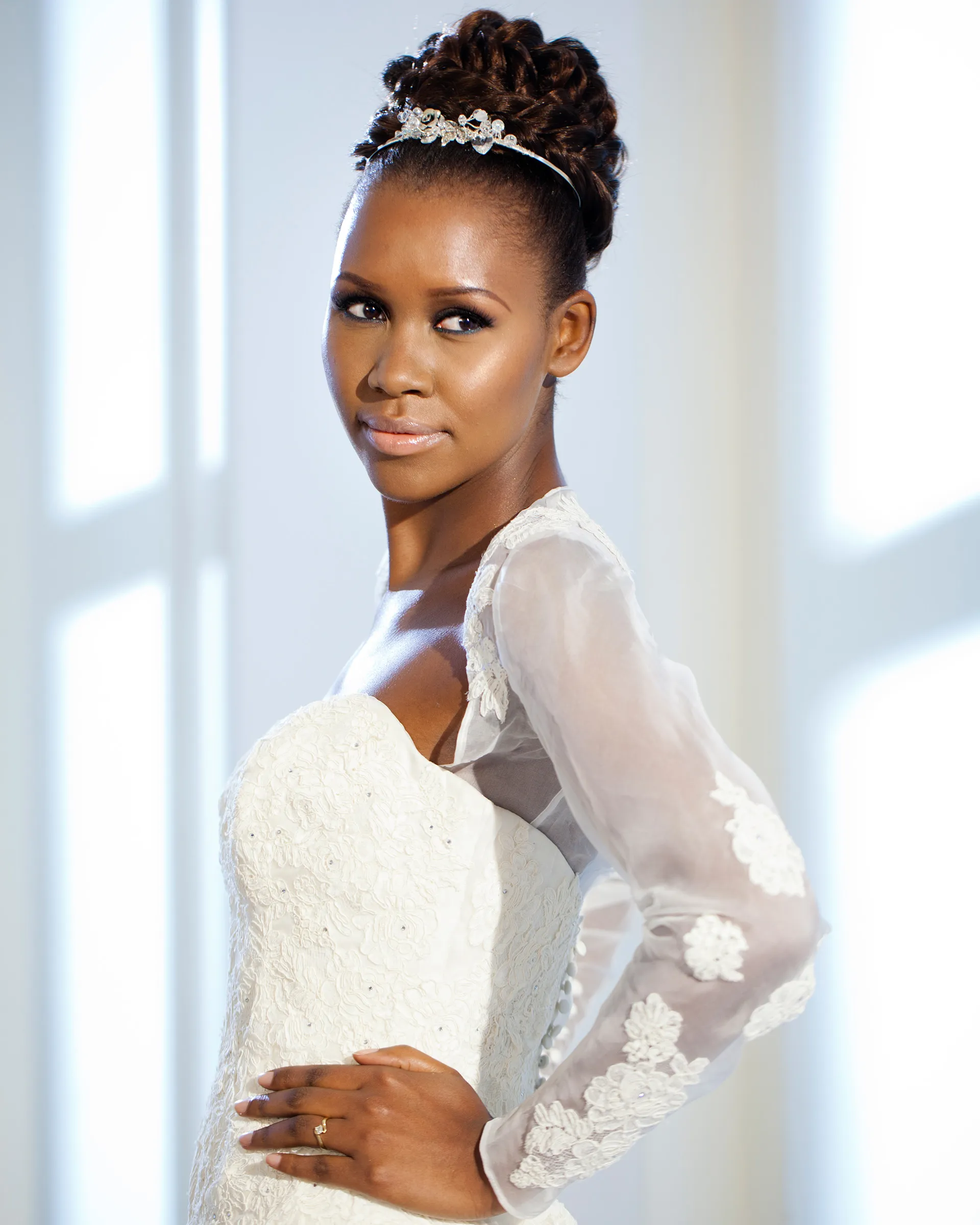 Alexandria, side, hand on hip: lace appliqués trail down the sheer organza sleeve, over the beaded lace of the strapless bodice.