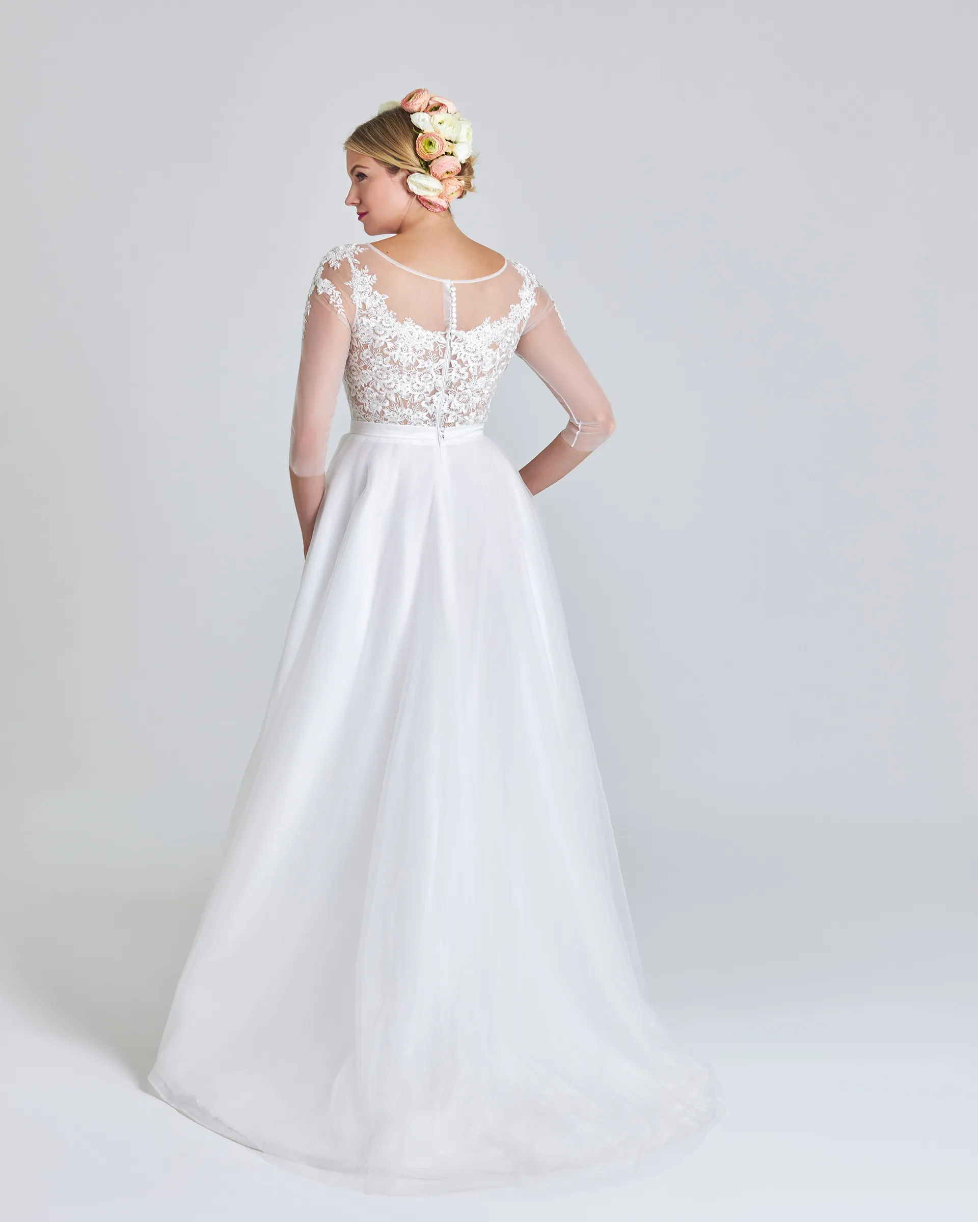 Ariyike, back: a sheer illusion back closed with a line of covered buttons, lace across the bodice and the gathered skirt sweeping behind.