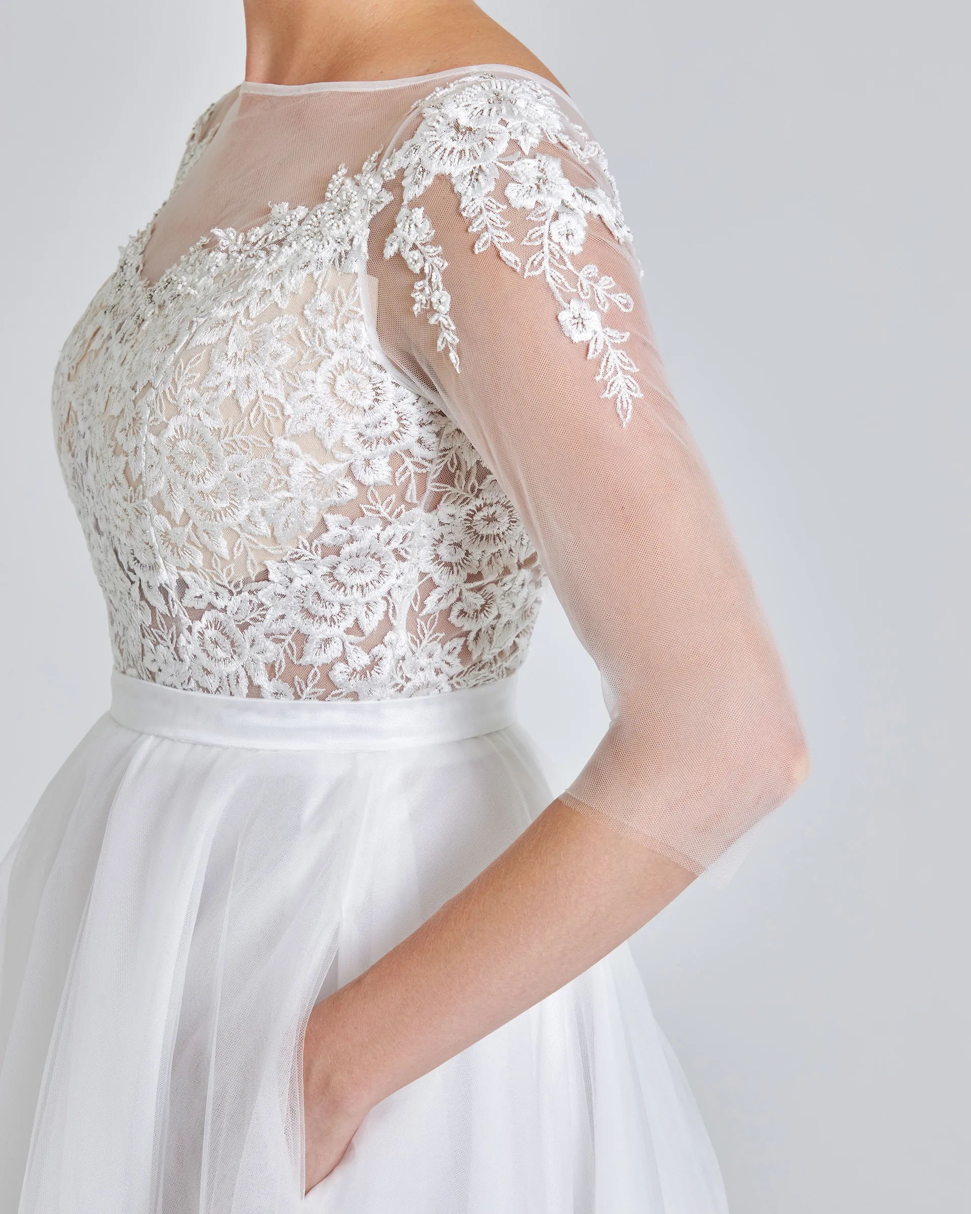 Ariyike, side detail: corded lace over the bodice, beaded appliqués spilling from the shoulder down the sheer tulle sleeve, and the slim waistband.