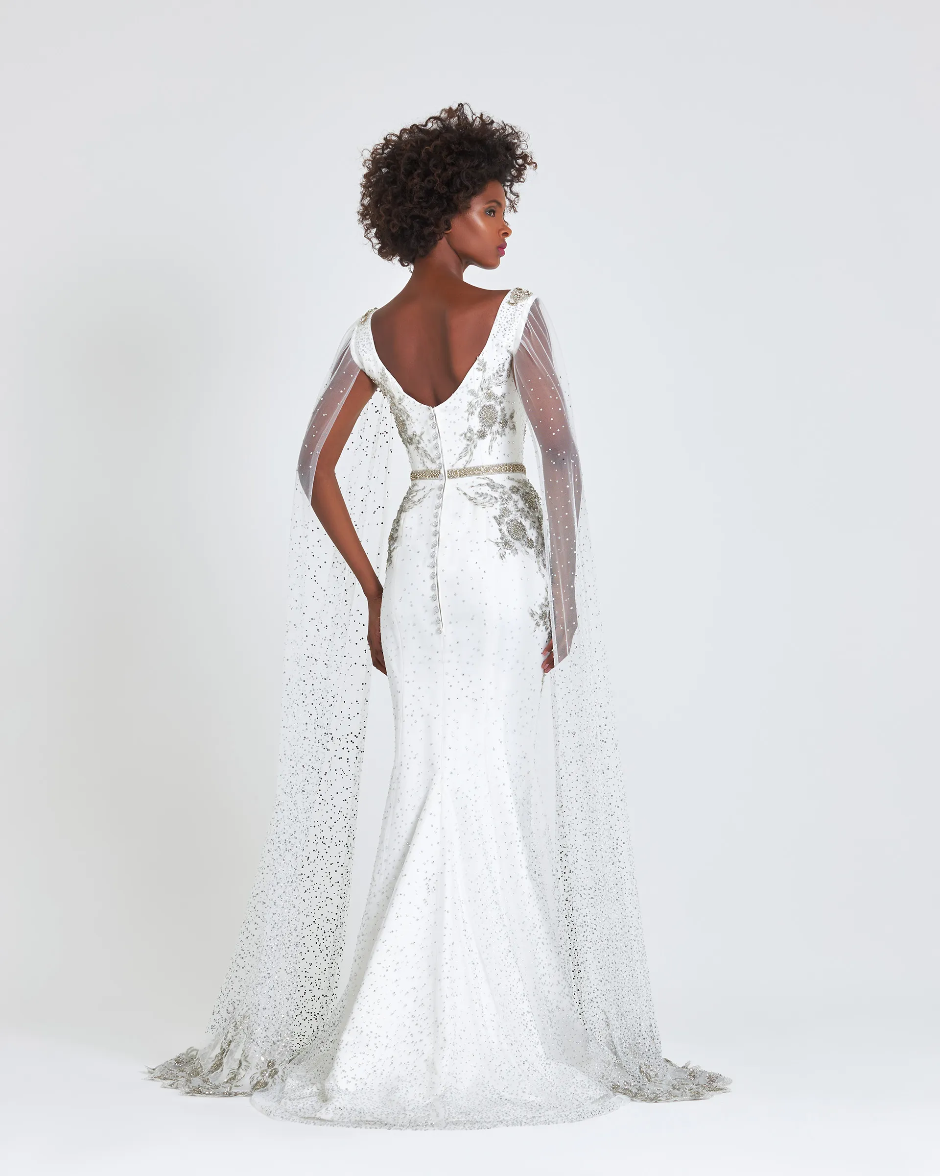 Ashake, back: a low scooped back between the cape sleeves, beaded appliqués at the waist and the crystal-studded tulle sweeping behind.