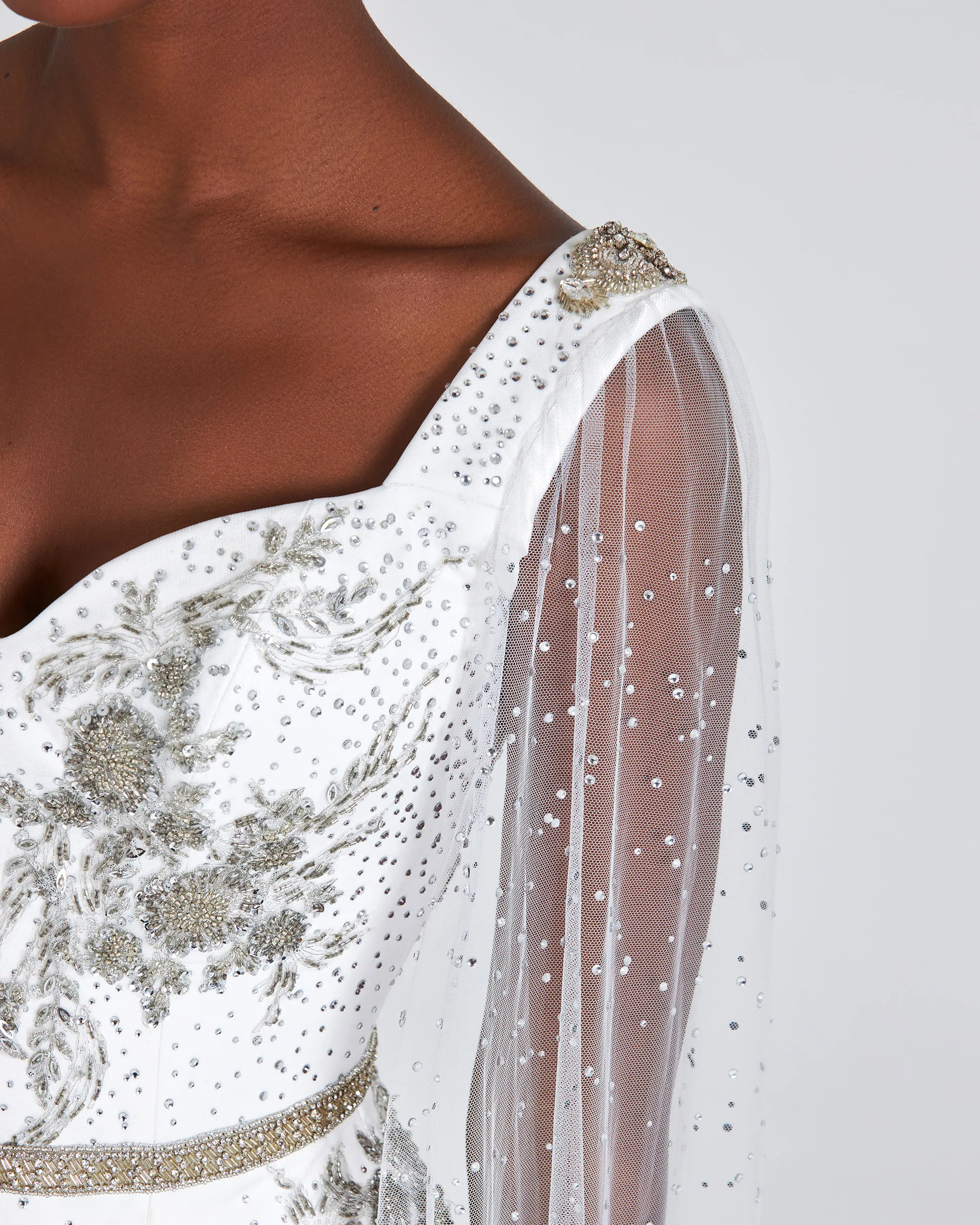 Ashake, front detail: silver bugle bead and crystal embroidery on the sweetheart bodice, a beaded brooch at the shoulder and sheer studded tulle falling as a sleeve.
