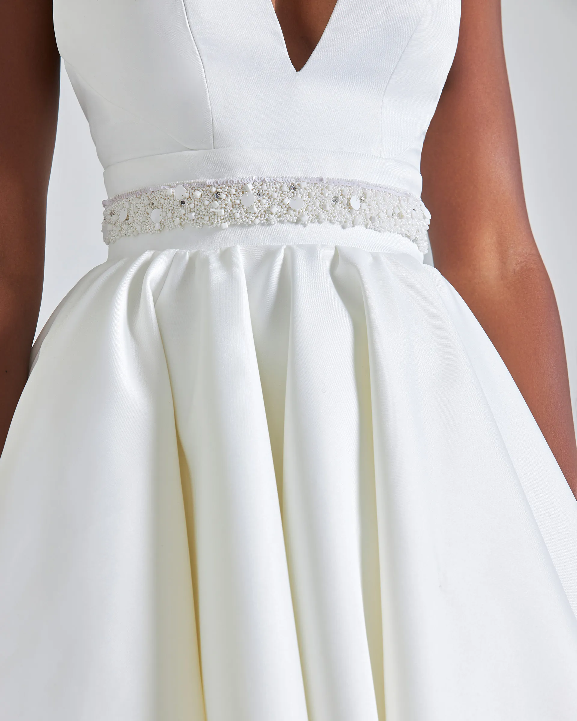 Ayo, front detail: the plunging neckline meeting a waistband of pearls, sequins and beads, above the deep folds of the zibeline skirt.