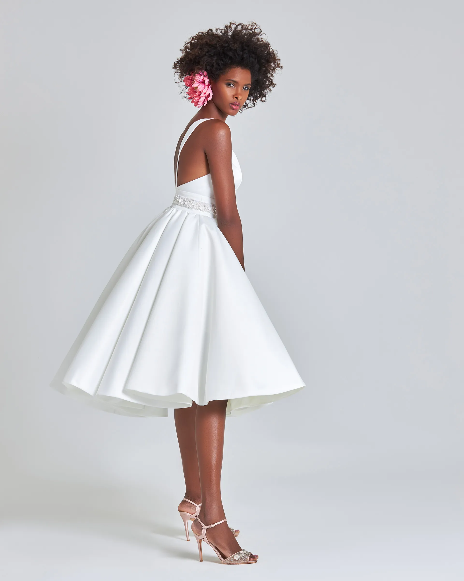 Ayo, side, mid-turn: the double-circle skirt swinging out at the knee, with straps running down an open back.
