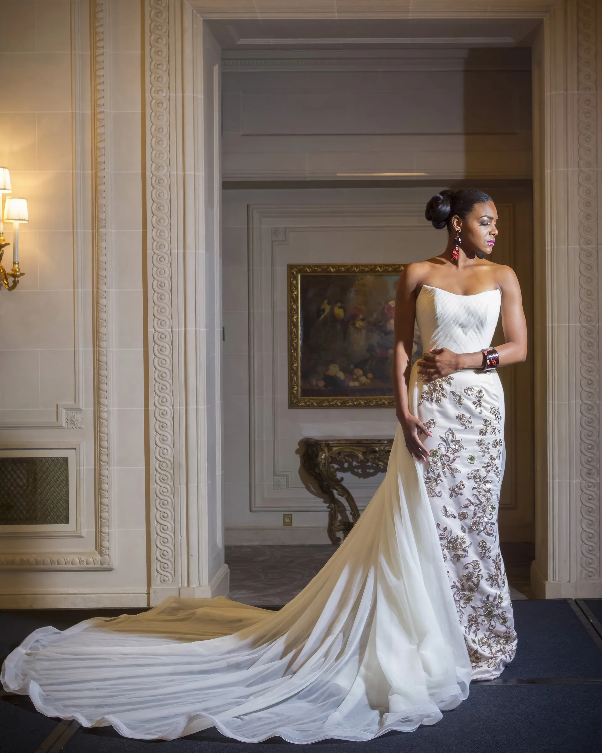 Calliope without the chemise, in a gilded salon: the strapless ruched tulle bodice, the appliquéd column skirt and the tulle overskirt sweeping out across the floor.