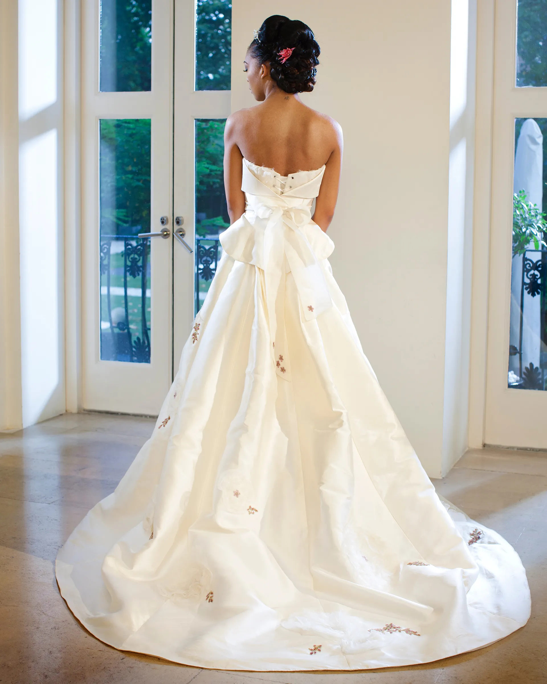 Ekatarina, back: a sculpted bow at the waist gathers the zibeline overskirt, which sweeps to the floor in a wide train dotted with beaded appliqués.