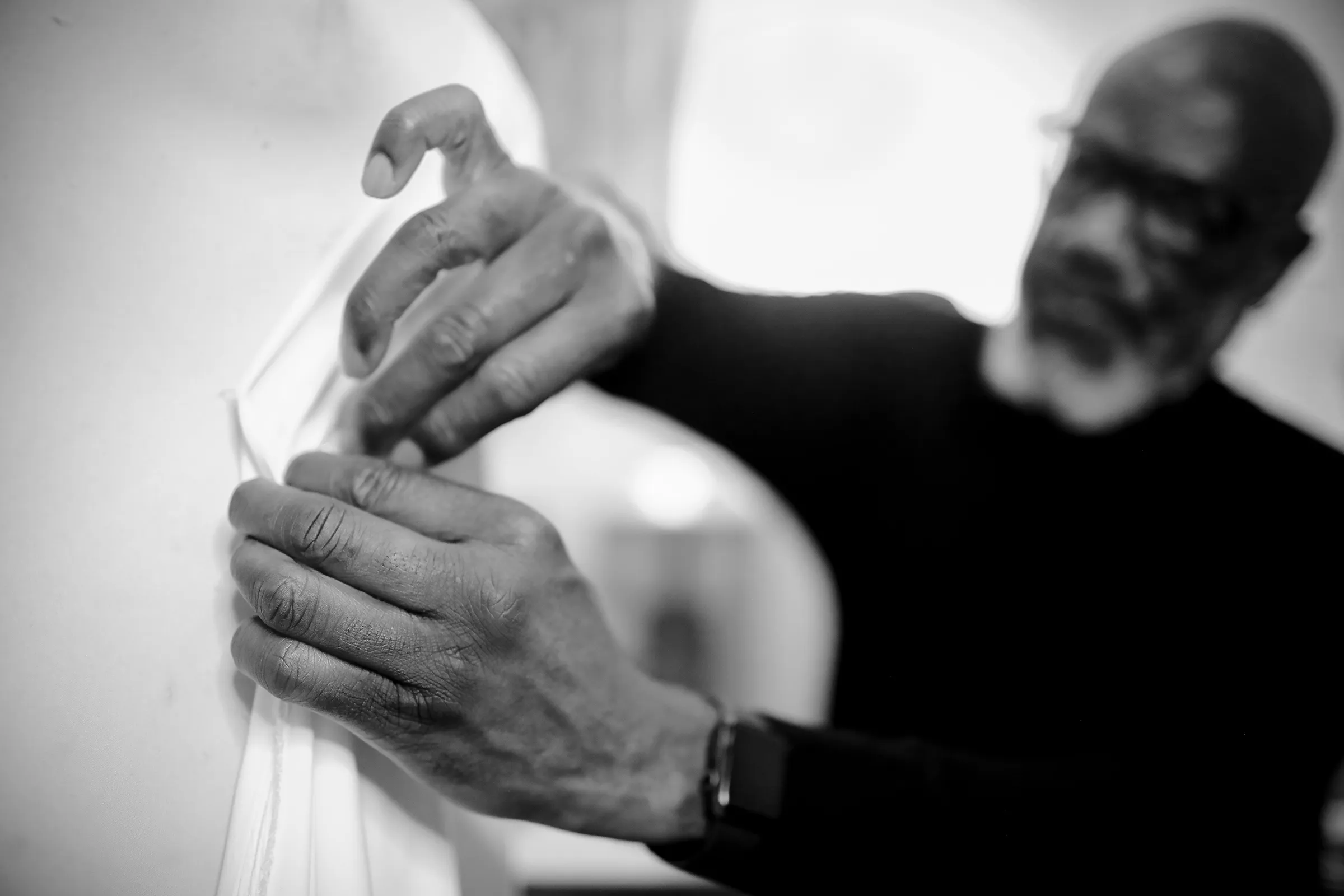 Yemi adjusting ruching on the bodice of a bride's gown in the atelier.