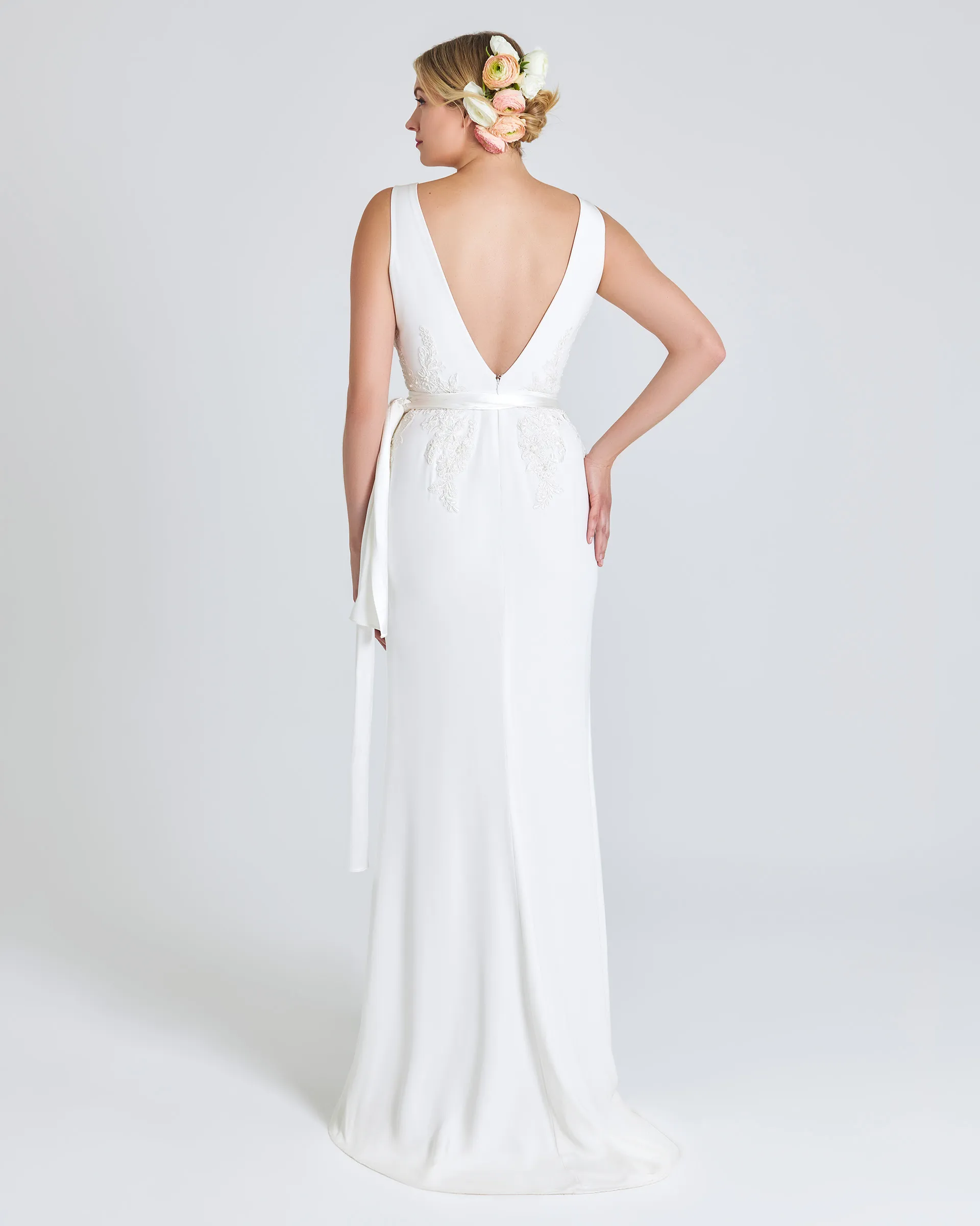 Tinuke, back: a deep V to the waistline framed by lace appliqués, with the sash ribbons trailing and the skirt pooling behind.