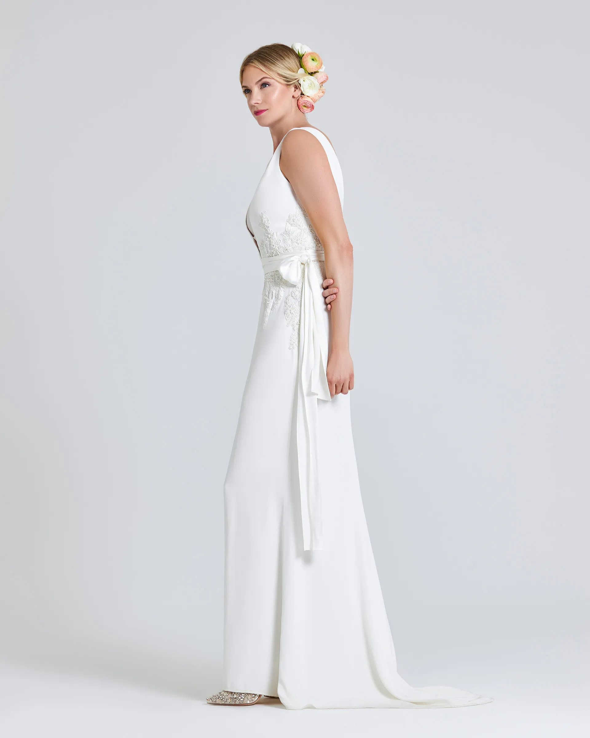 Tinuke, side: the sash falls in long ribbons down the left side, and the slim crepe skirt runs to a short train.