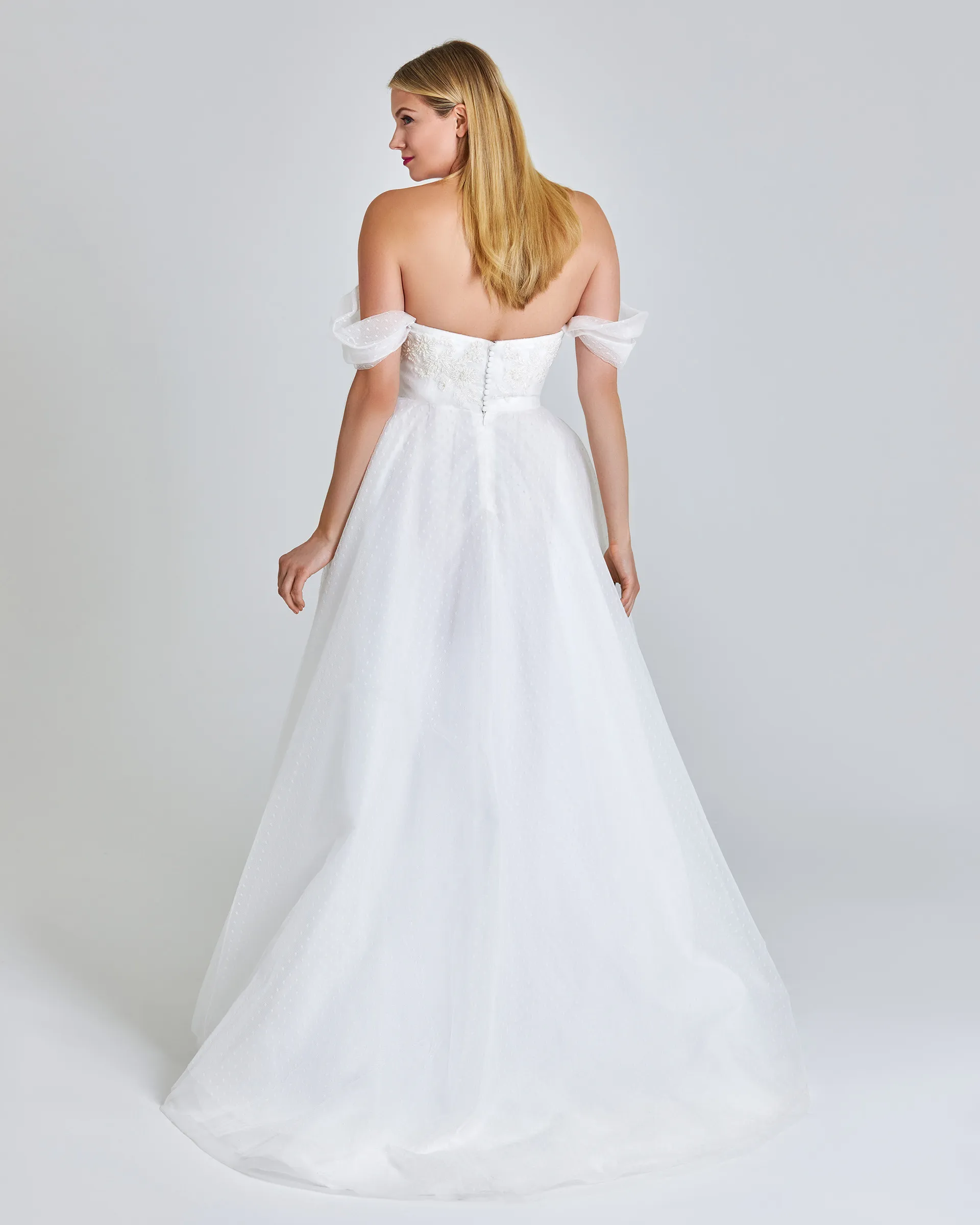 Toke, back: off-the-shoulder sleeves frame bare shoulders, covered buttons close the bodice and the tulle skirt sweeps behind.