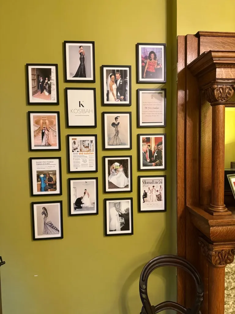 A wall of framed photographs, fashion sketches and press cuttings beside the oak mantel.